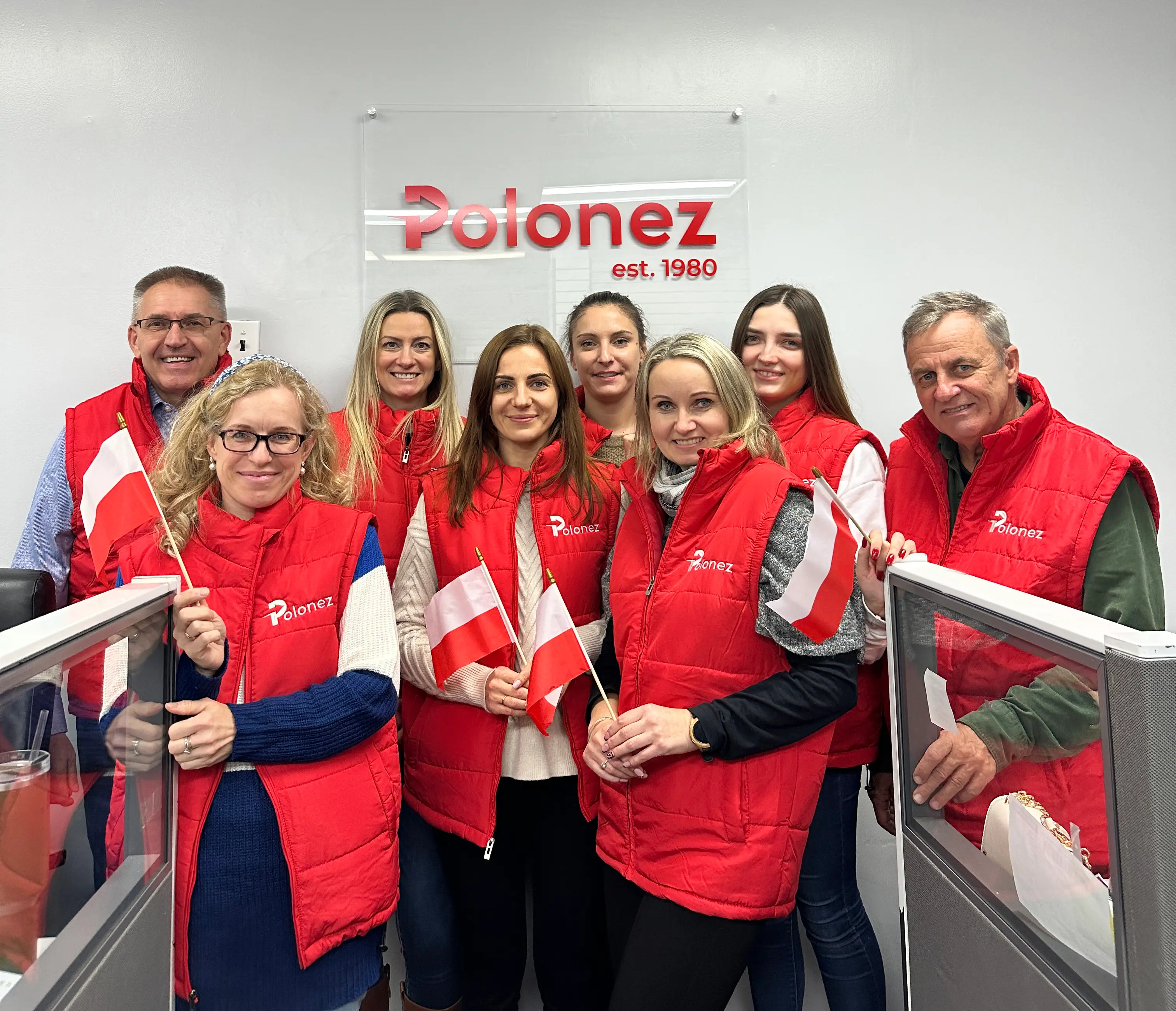 Polonez Express team in red branded vests holding Polish flags at the Schaumburg office.